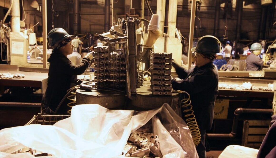 Foundry workers handling stacks of gray iron castings.